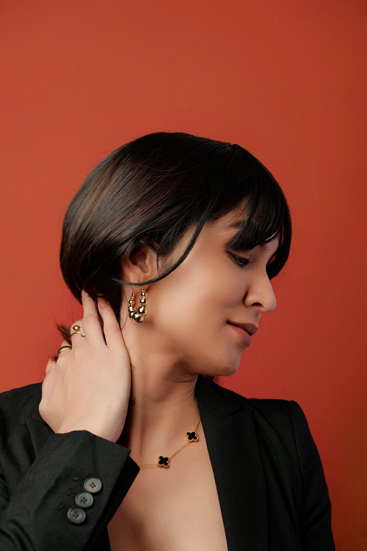 Woman adjusting her earrings against a red background